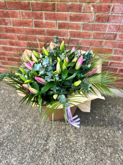 Pink Lily Handtied - A sophisticated hand-tied bouquet featuring elegant pink oriental lily buds complemented by fresh eucalyptus and lush palm foliage. Designed to bloom beautifully over time, this arrangement offers lasting beauty, delicate fragrance, and timeless style—perfect for birthdays, anniversaries, thank-you gifts, or simply brightening someone's day.