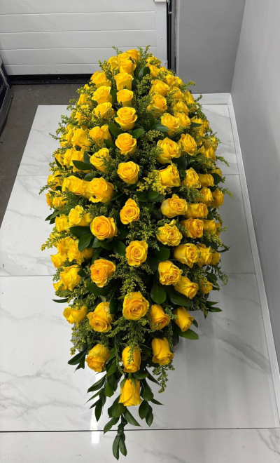 Yellow Rose Spray - A magnificent full-length casket spray designed in radiant golden yellow tones with rich green foliage, creating a striking and heartfelt tribute. Elegantly arranged with abundant blooms and graceful flowing lines, this design symbolises friendship, gratitude, cherished memories, and a life beautifully lived. Thoughtfully handcrafted to honour a beloved family member or friend, it offers a meaningful expression of sympathy, comfort, and respect, providing a warm and dignified centrepiece for funeral and memorial services.