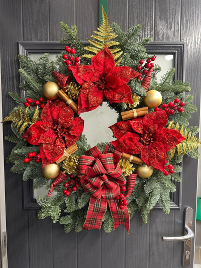 Classic Festive - Create a warm and welcoming entrance with the Classic Festive Elegance Wreath. Handcrafted with fresh evergreen foliage, this luxurious design is beautifully decorated with rich red and gold accents, natural pine cones, cinnamon bundles, decorative berries, shimmering ornaments, glittering seasonal details, and finished with a timeless tartan bow. Blending traditional colours with elegant festive styling, this wreath is a stunning addition to your Christmas décor and a perfect way to celebrate the season.
