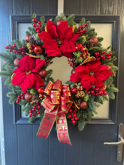 Yuletide Elegance - Add a touch of timeless festive luxury to your home with the Yuletide Elegance Christmas Wreath. Handcrafted with fresh evergreen foliage, this stunning design is adorned with rich red seasonal accents, sparkling ornaments, natural pine cones, dried orange slices, decorative berries, and a beautifully patterned festive ribbon. Combining traditional Christmas colours with elegant detailing, this wreath creates a warm and welcoming display that will brighten any entrance throughout the holiday season.