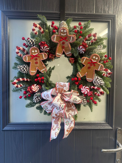 Gingerbread Man - Add a touch of festive fun to your home with the Gingerbread Christmas Wreath. Handcrafted with fresh evergreen foliage, this cheerful design features adorable gingerbread characters, striped candy canes, peppermint sweets, frosted pinecones, vibrant red berry accents, and a beautifully coordinated festive ribbon. Bursting with classic Christmas colours and sweet-inspired charm, this wreath creates a warm, welcoming display that's perfect for celebrating the magic of the season.
